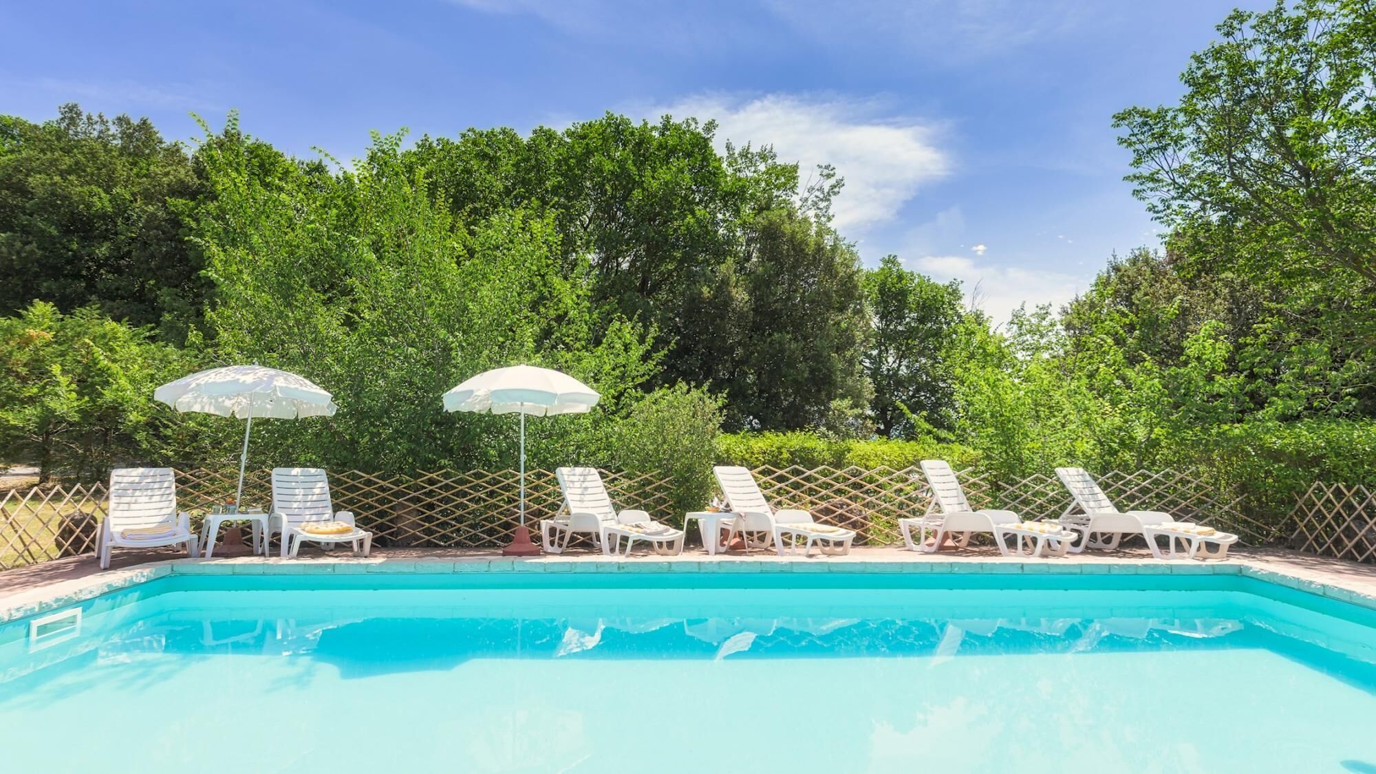 Une piscine avec des chaises longues et des parasols.