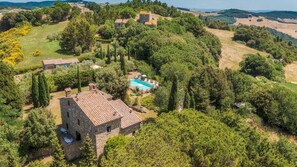 An aerial view of a countryside property with stone buildings, a swimming pool, and surrounding greenery. - Podere Orcio 10 in Volterra (Volterra)