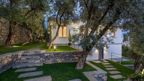A modern house with a stone pathway leading to the entrance, surrounded by lush greenery and trees. - Villa Scirocco 10 2 in Pieve Ligure (Pieve Ligure)