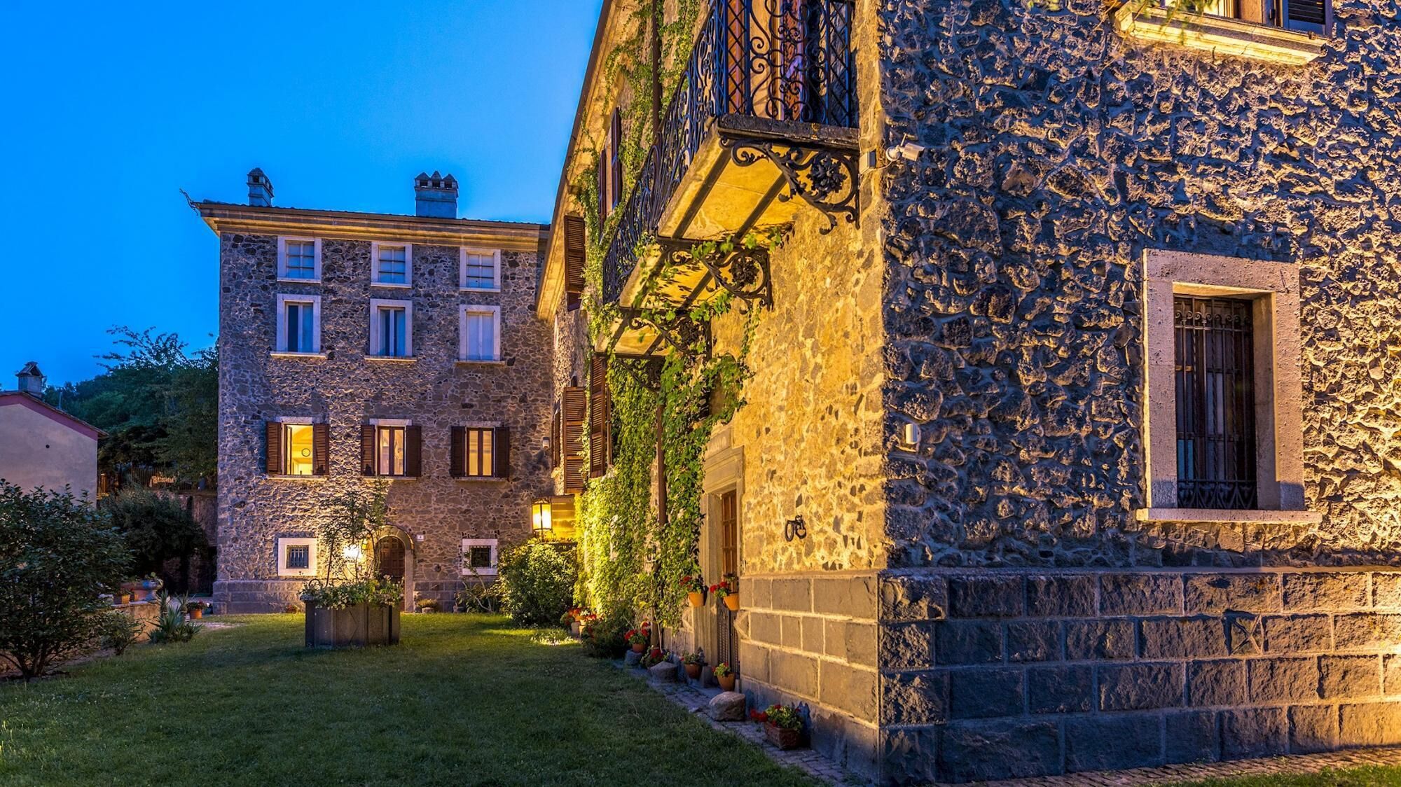 A stone building with a garden and a smaller stone building with a balcony.