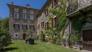 A stone building with multiple windows and a garden in front.