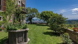 Ein Steinhaus mit Balkon, einem grünen Rasen und Blick auf eine ferne Stadt.