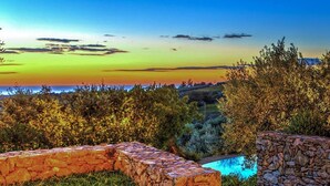 A stone wall, a stone pool, and a building with a tiled roof. - Villa Le Cave 12 in Campalto (Campiglia Marittima)