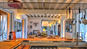 A modern kitchen with a central island, stainless steel appliances, and a large window providing natural light. - Villa Le Cave 12 in Campalto (Campiglia Marittima)