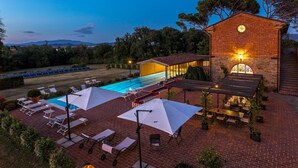 A rooftop pool area with lounge chairs and umbrellas, a brick building with a clock, and a view of distant mountains. - Antica Villa Merelli 24 (Monte San Savino)