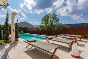 A poolside area with lounge chairs and a decorative column. - Il Nido 2 2 in Staggiano (Arezzo)