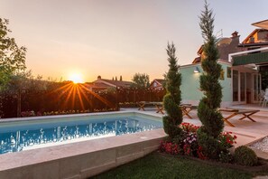 A swimming pool with a clear view of the sunset, surrounded by a well-maintained garden and a patio area with outdoor furniture. - Il Nido 2 2 in Staggiano (Arezzo)