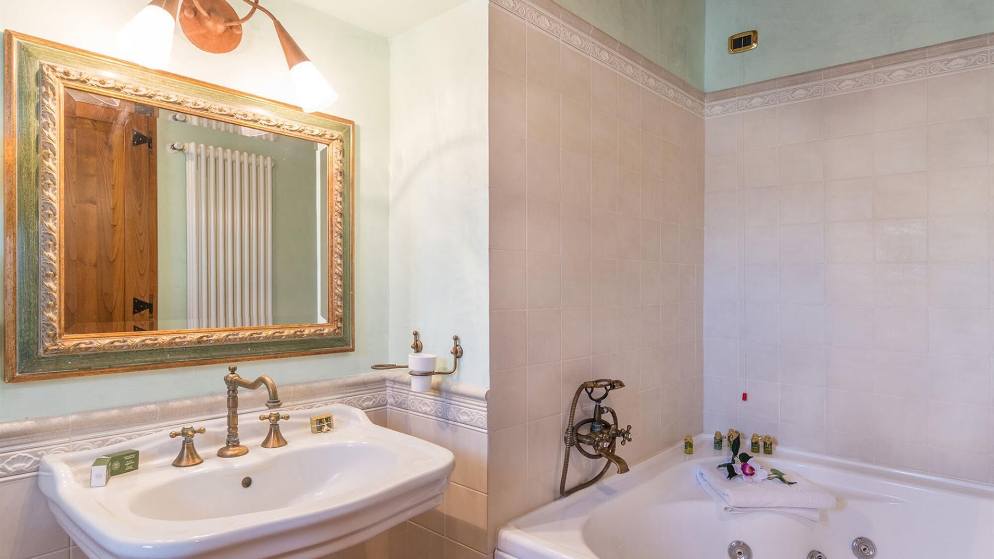 A bathroom with a sink, mirror, and bathtub.