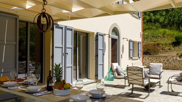 A sunlit outdoor dining area with a table set for two, featuring a bowl of fruit, wine glasses, and a bottle of wine. - Fc-f139-mini0at - Villa Mia 6 (Mercato Saraceno)