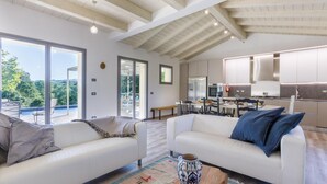A modern living room with two white sofas, a coffee table, and a view of a swimming pool and greenery outside. - Fc-f139-mini0at - Villa Mia 6 (Mercato Saraceno)