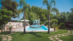 Un área de piscina con una hamaca, sillas de descanso y un pequeño pabellón.