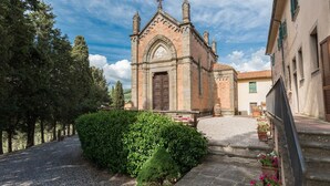 Eine historische Kirche mit einem markanten Eingang, umgeben von einem Kiesweg und üppigem Grün.