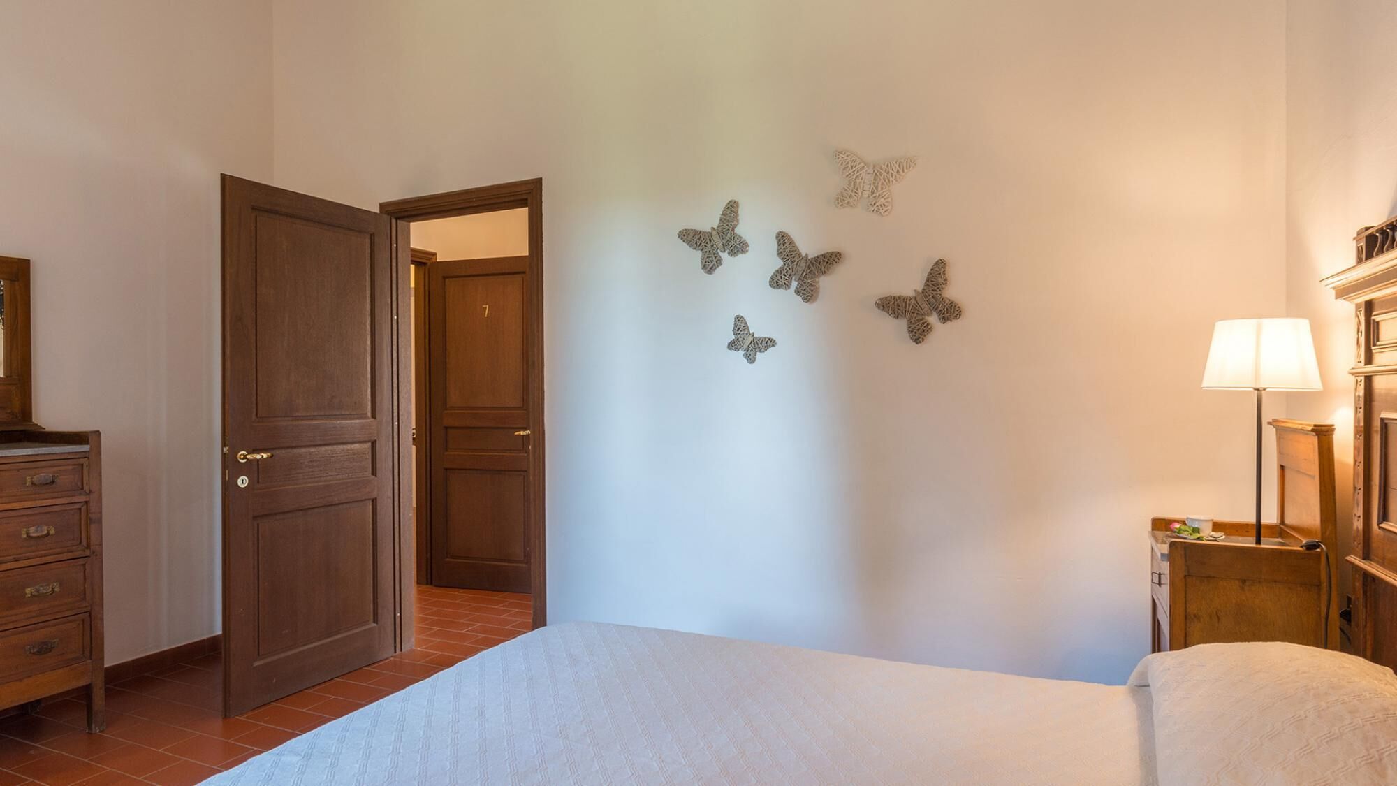 Un dormitori amb llit, un armari, una porta i decoració mural.