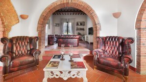 A living room with two leather armchairs, a white coffee table, and a red sofa.