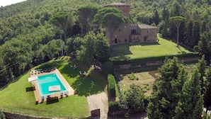 Une villa dotée d’une piscine, entourée d’une végétation luxuriante et agrémentée d’une tour.