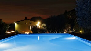 A swimming pool at dusk with a house in the background. - Lu-b648-capa0at - Villa Alida 12 (Capannori)