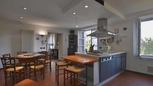 A modern kitchen with a central island, wooden chairs, and a dining table. - Lu-b648-capa0at - Villa Alida 12 (Capannori)