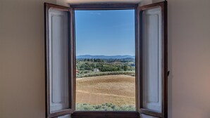 An open door with a view of a vineyard and distant hills.