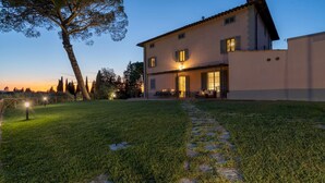 A two-story house with a covered patio and a well-maintained lawn.