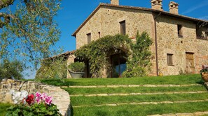 A stone building with a large arched entrance, a grassy front yard, and a clear blue sky.