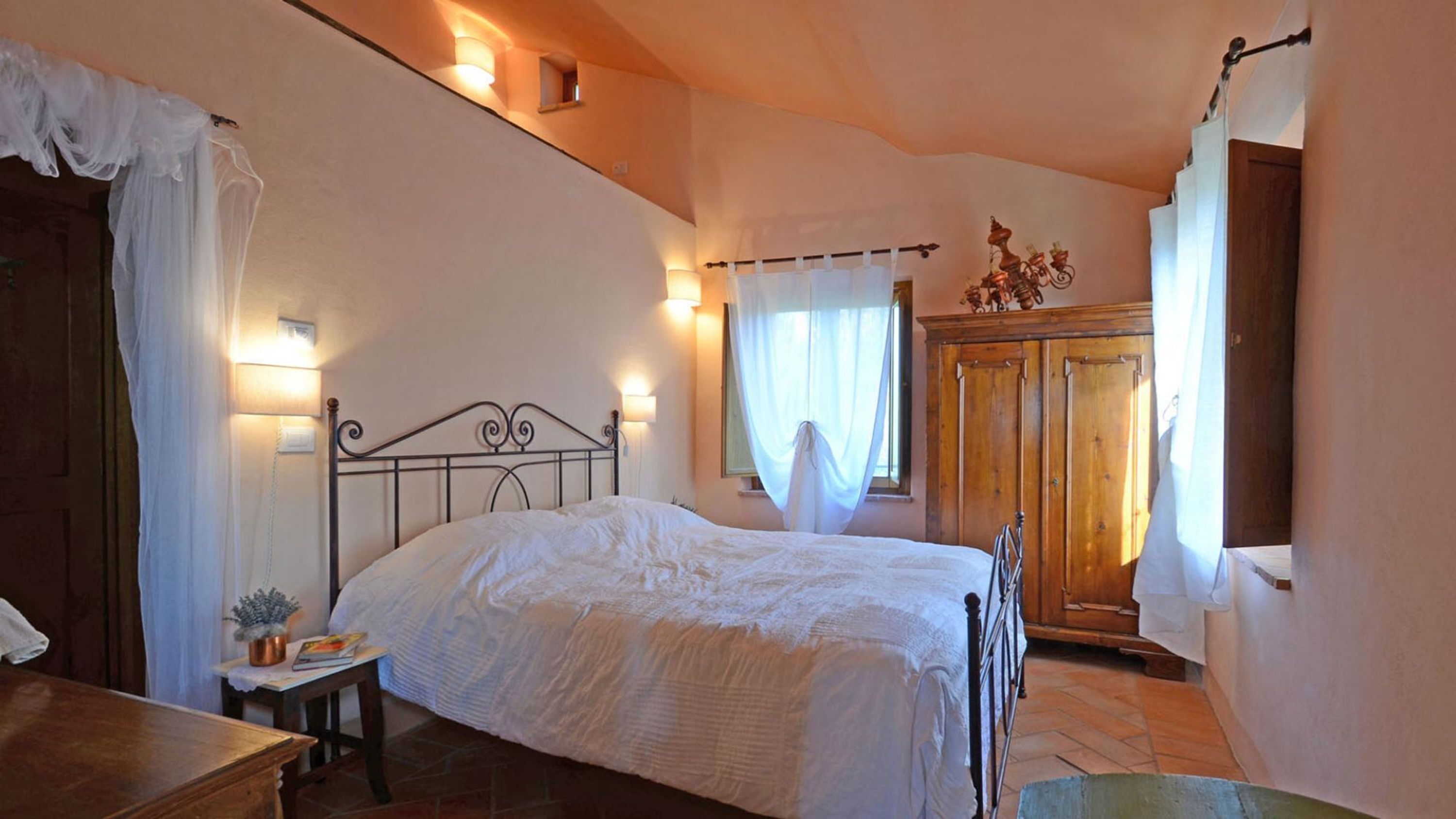 A bedroom with a bed, bedside table, lamp, and curtains.