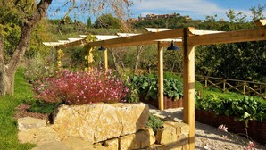 Een houten pergola met een stenen bank en potplanten.