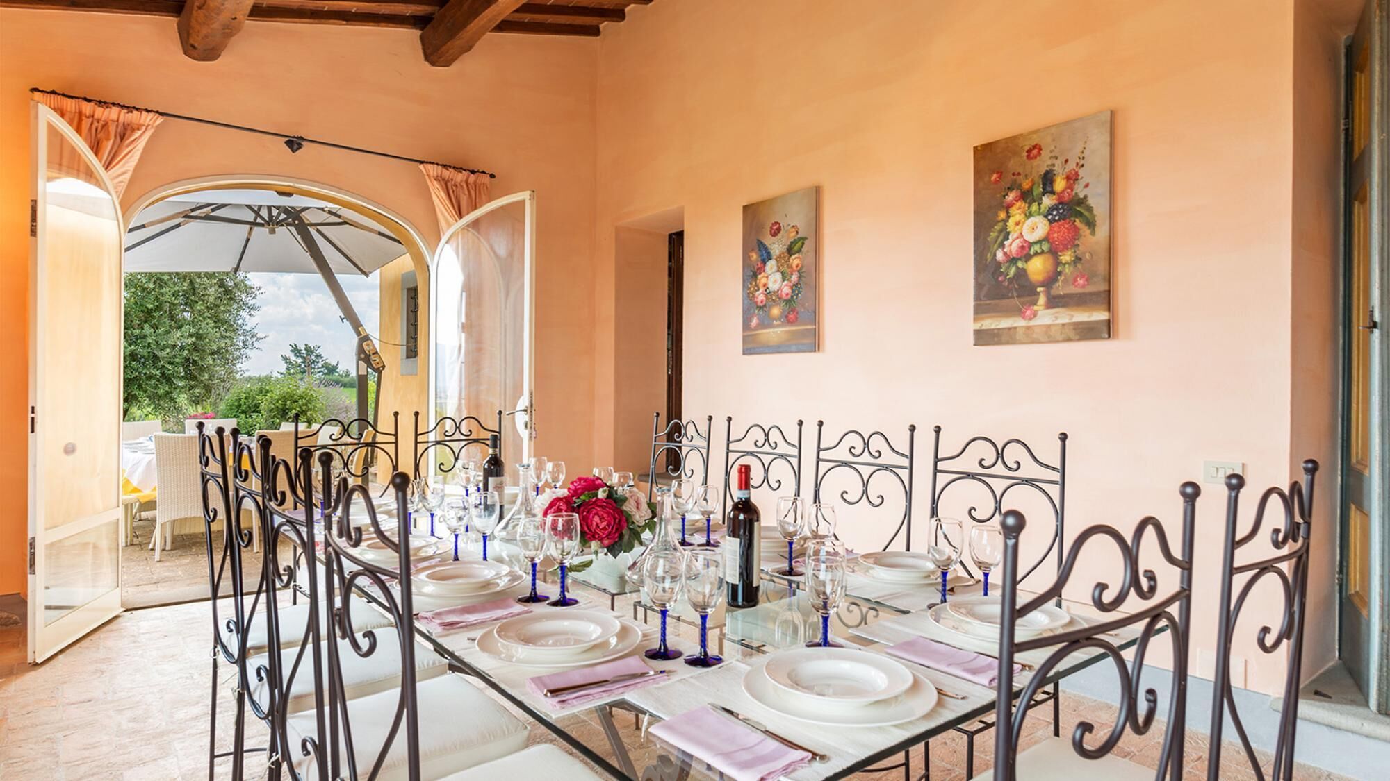 A dining area with a long table set for a meal, surrounded by metal chairs with intricate designs.