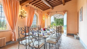 A dining area with a long table set for a meal, surrounded by chairs with cushioned seats. - Ar-f628-mssa0at - Villa Pucci 12 (Monte San Savino)