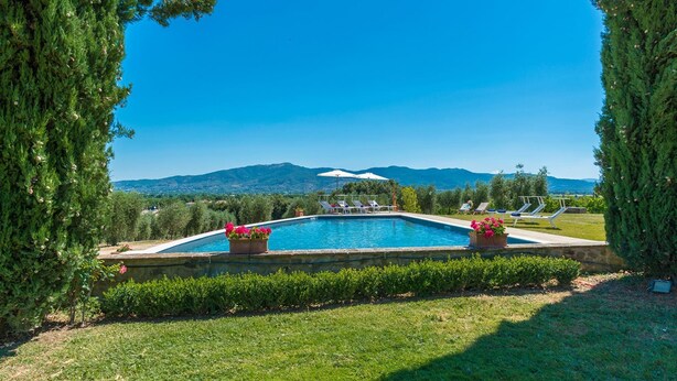 A rectangular swimming pool with a view of mountains in the background, surrounded by greenery and a few lounge chairs. - Ar-f628-mssa0at - Villa Pucci 12 (Monte San Savino)