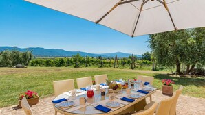 An outdoor dining area with a table set for six, surrounded by wicker chairs. - Ar-f628-mssa0at - Villa Pucci 12 (Monte San Savino)