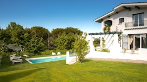 A modern house with a swimming pool, white exterior, and a well-maintained lawn.