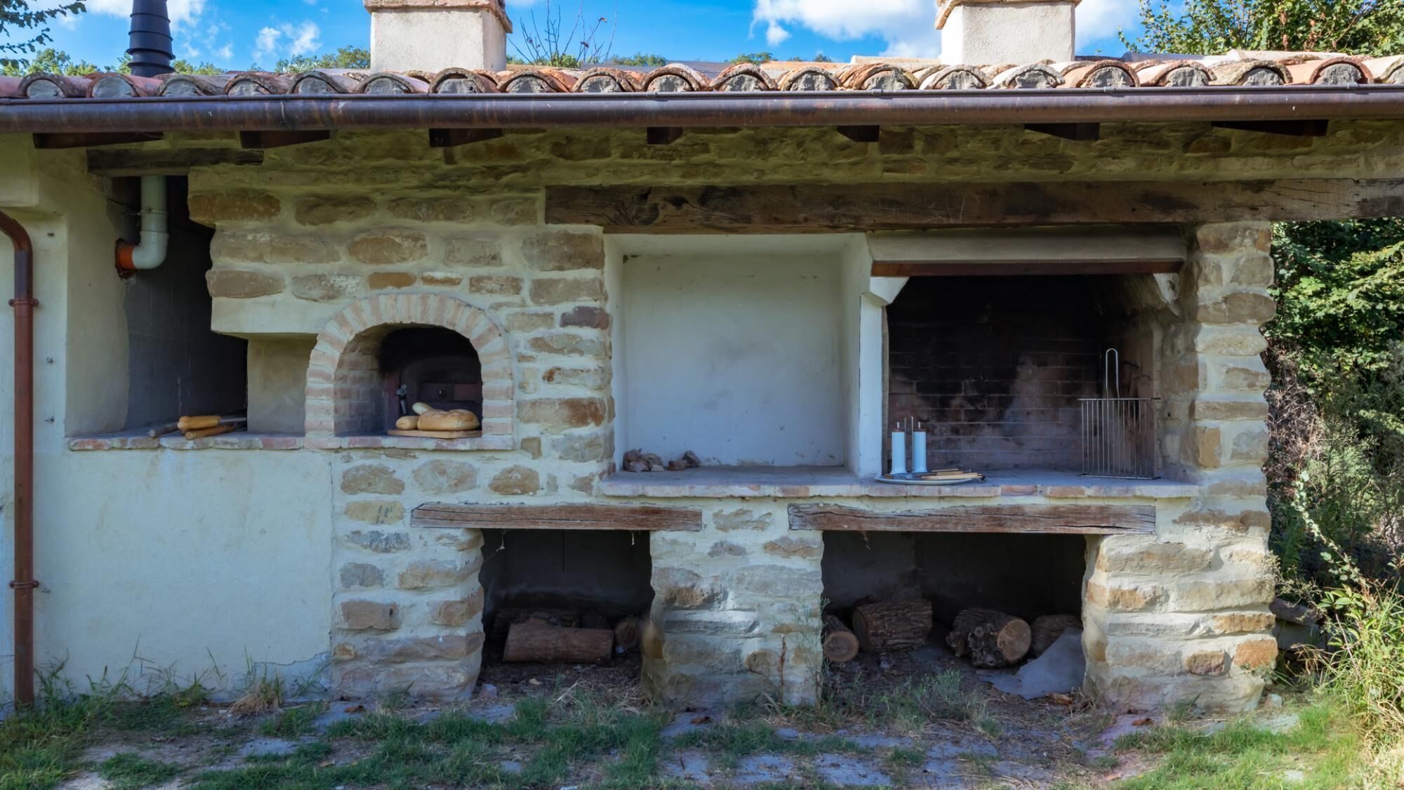 Un bâtiment en pierre avec un toit en tuiles, un four en briques et une cheminée.