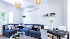A modern living room with a sectional sofa, a glass coffee table, a dining table with chairs, and decorative plants. - Li-c415-vipo0at - Il Nocciolo 12 (Cecina)