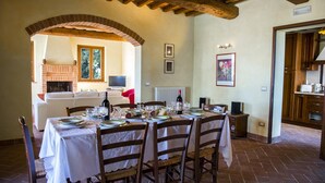 A dining area with a brick fireplace, a TV, and a dining table set for four.