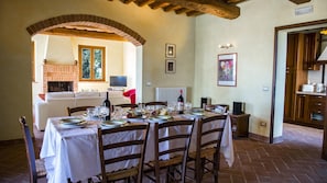 A dining area with a brick fireplace, a TV, and a dining table set for four.