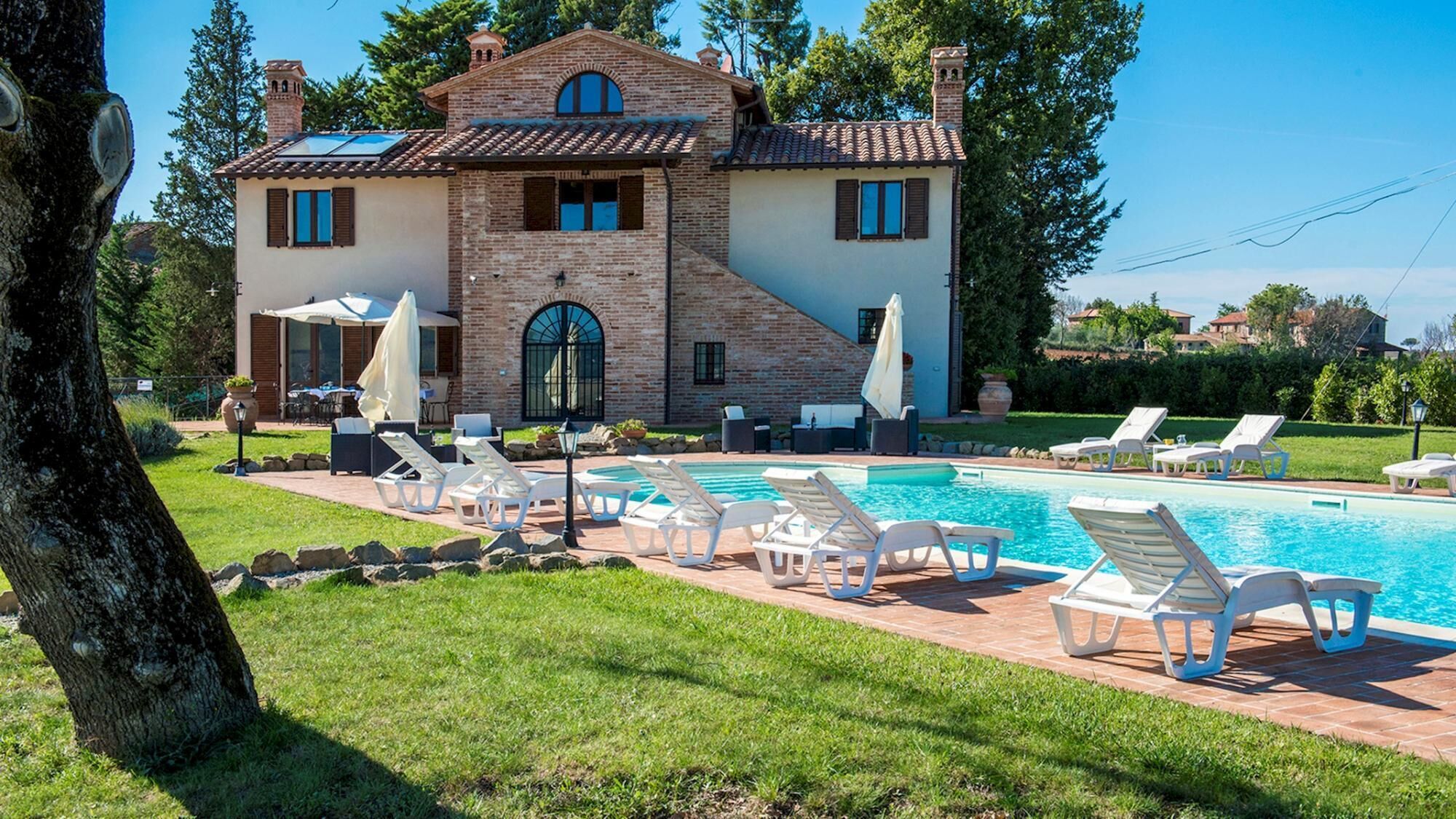 A large house with a swimming pool, outdoor seating, and a well-maintained lawn.