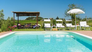 Uma piscina com espreguiçadeiras e um pérgula.
