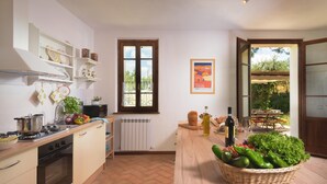 Cozinha com fogão, pia e janela com vista para um jardim.