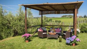 A covered outdoor seating area with wicker furniture and potted flowers. - Pg-c309-lfrt0at - Poggio Vistabella 10 (Castiglione del Lago)