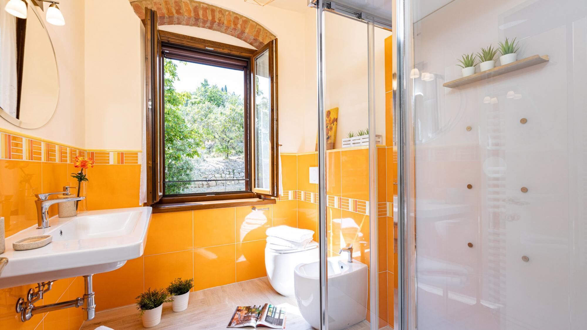 A bathroom with a window, a sink, a toilet, and a shower.