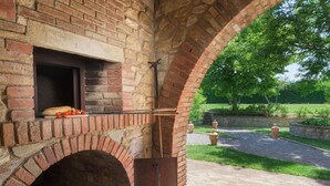 A brick oven with a window, a loaf of bread, and tomatoes on a cutting board. - Pg-g601-voan6at - Villa Augusto 10 (Piegaro)