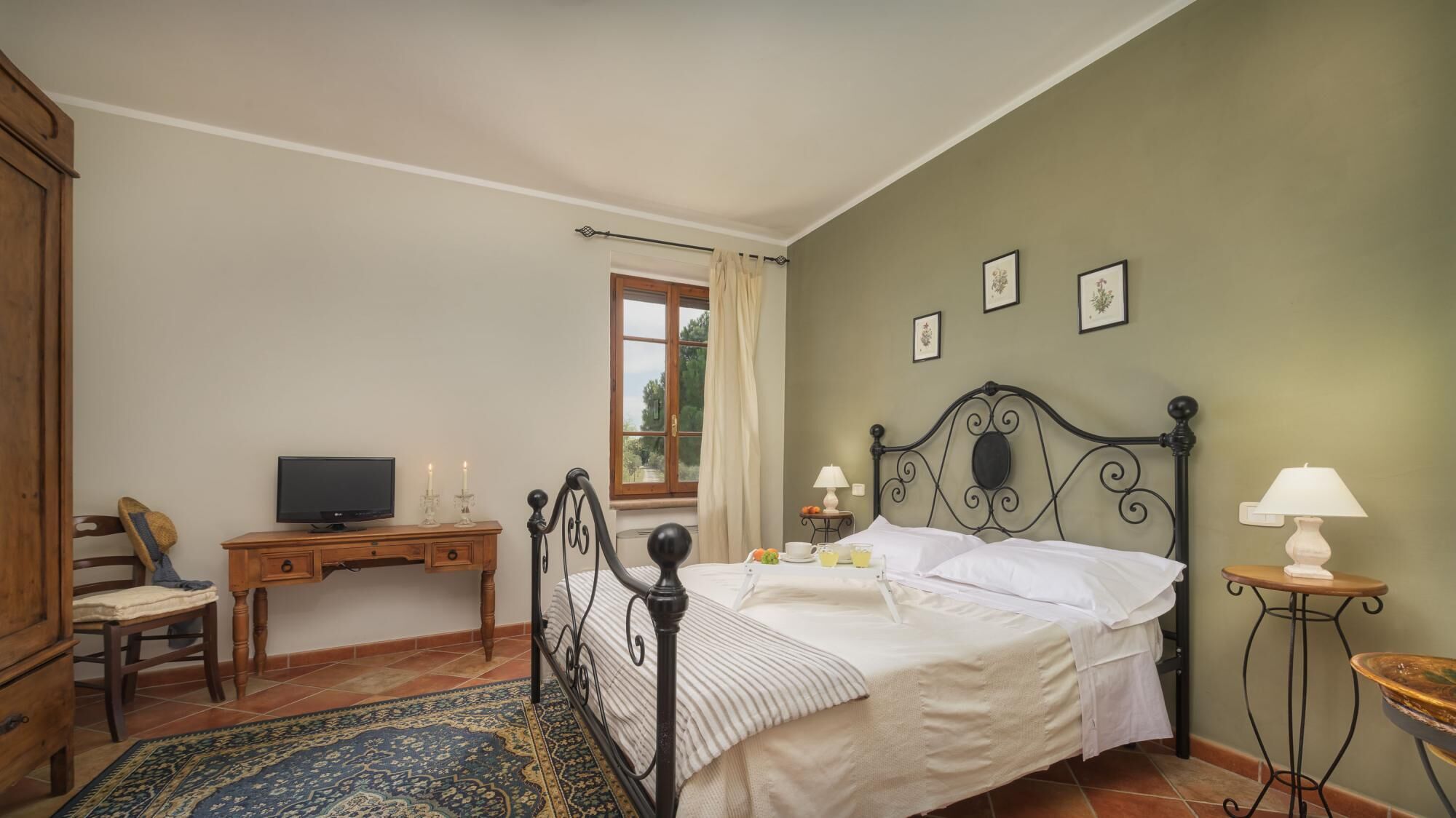Un dormitorio con una cama, un escritorio, una silla, un televisor y una ventana.