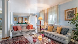 Ein geräumiges Wohnzimmer mit einer großen Sofagarnitur, einem Couchtisch mit Dekoration und einem Essbereich mit Tisch und Stühlen.