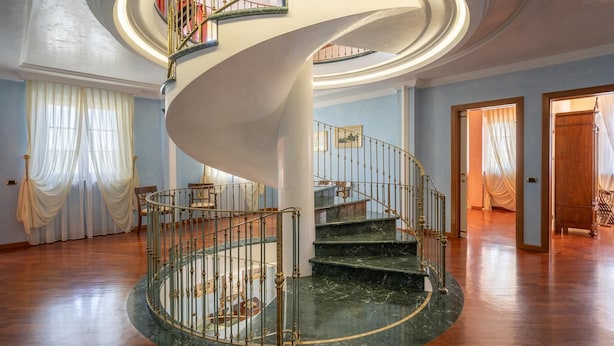 Eine prächtige Wendeltreppe mit Marmorstufen und aufwendiger Metallreling, die zu einer oberen Etage führt.