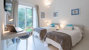 Ett hotellrum med två sängar, ett skrivbord med en bärbar dator och en stol.