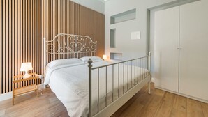 Un dormitorio con cama, mesita de noche, lámpara, armario y un diseño de pared con listones.