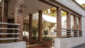 Un edificio moderno con vestíbulo cubierto, columnas de ladrillo y plantas en macetas.