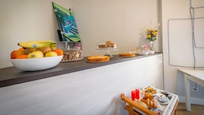 Un bufé de desayuno con frutas, pasteles y un jarrón con flores.