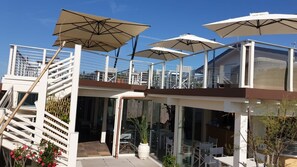 A modern outdoor seating area with white umbrellas, glass railings, and potted plants. - Ms-f023-manz11at - Il Renzito 8 (Montignoso)