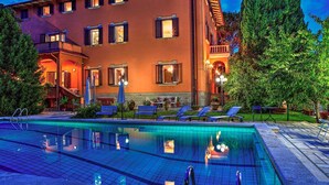 A hotel with a swimming pool, outdoor seating, and a well-lit facade. - Pg-c990-dfio19at - Villa Michelangelo 14 (Corciano)